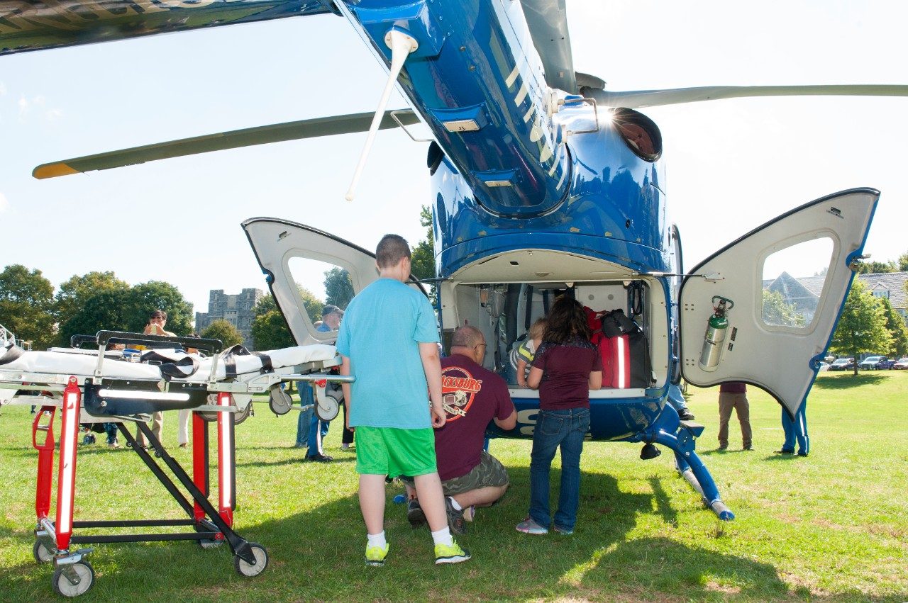 An onlooker observes people working on a helicopter.