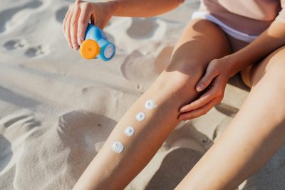 A sunbather applying sunscreen to her leg. Image courtesy Pexels.