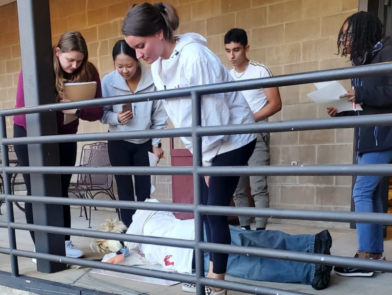 A group of students examines a fake crime scene