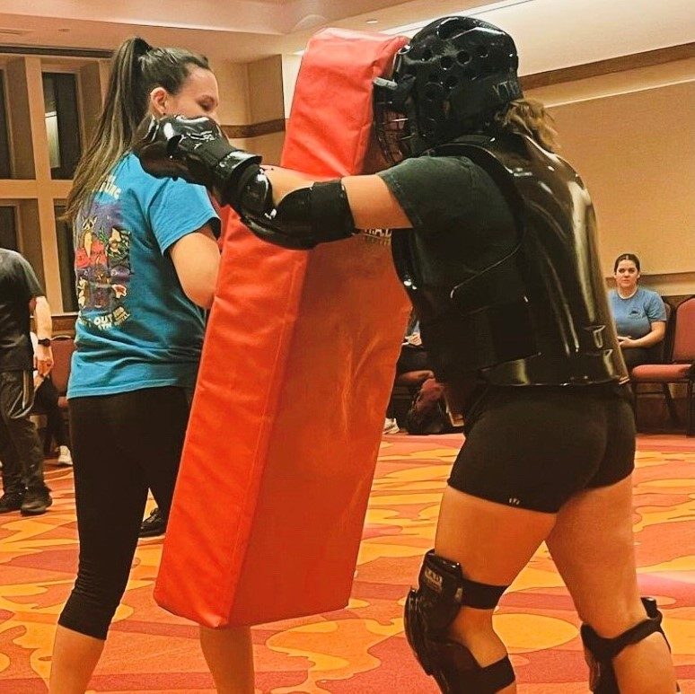 A participant punches a RAD Red bag held by a female RAD instructor